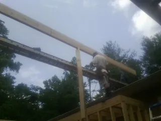 Carpenter setting a ridge beam over a new addition frame — Ice Dam Removal by Roofing Brothers in Arkport
