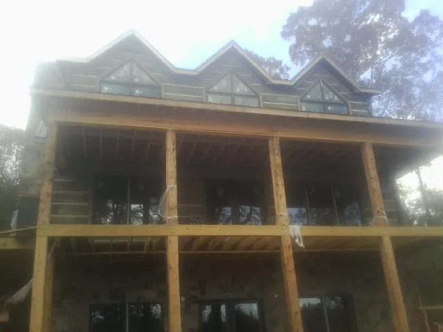 Dormers and porch framing on a large log home under construction — Roof Coating work by our crew in Arkport