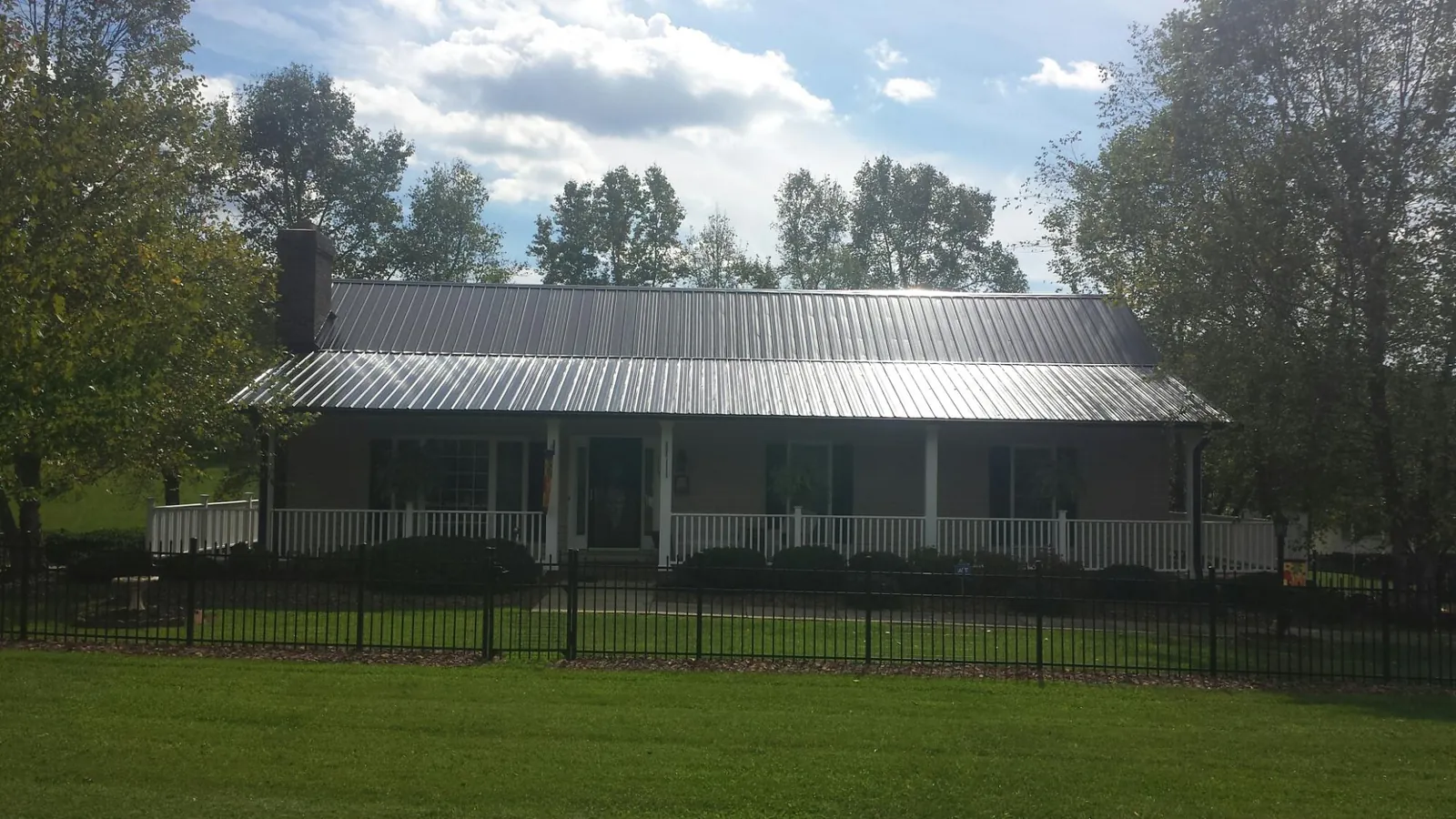 Gray metal roof on a brick ranch with a full width front porch — Gutter Guard Installation work by our crew in Arkport
