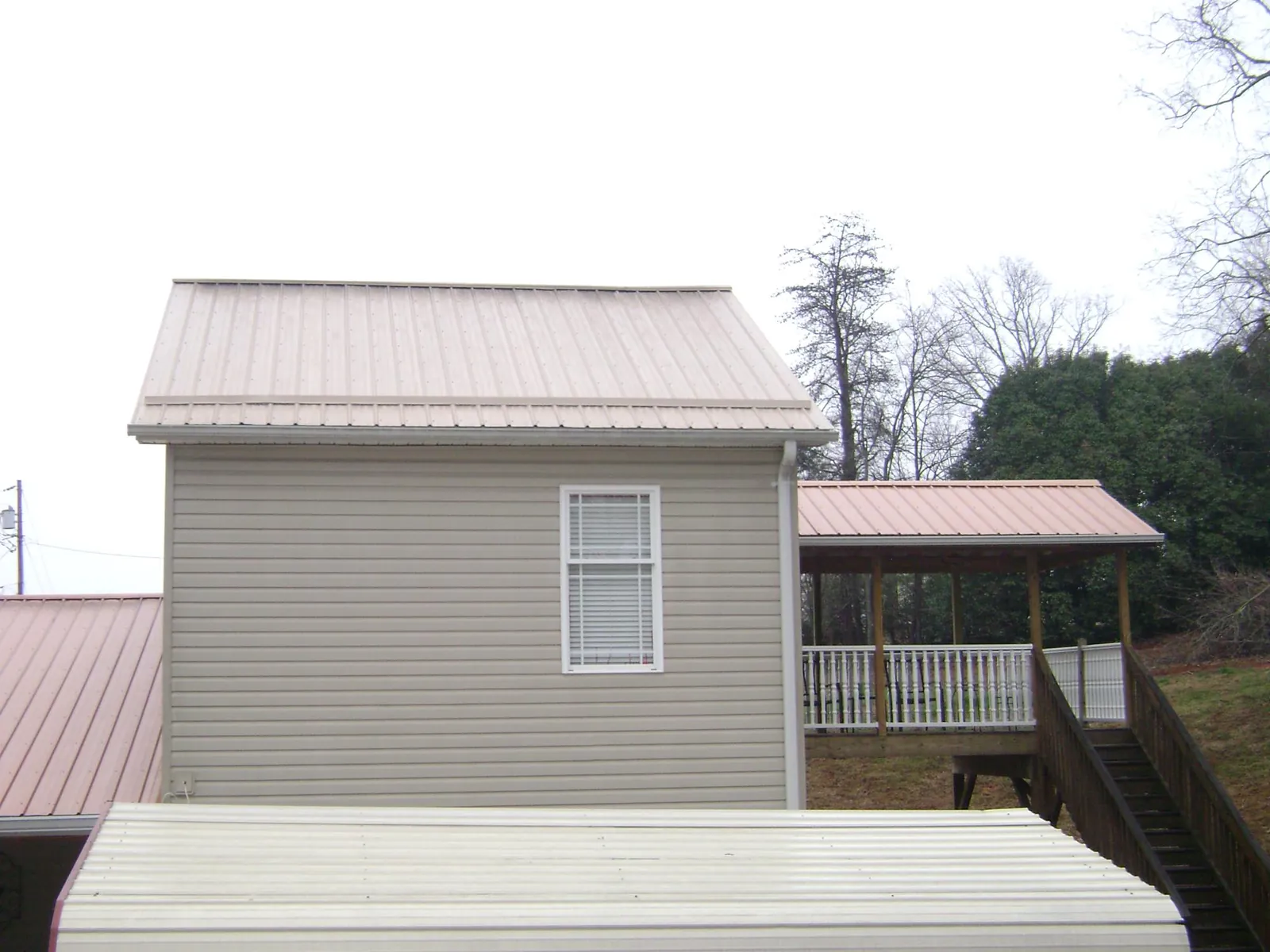 Tan metal roofs on a two story addition and attached porch, from a Roof Replacement job in Arkport