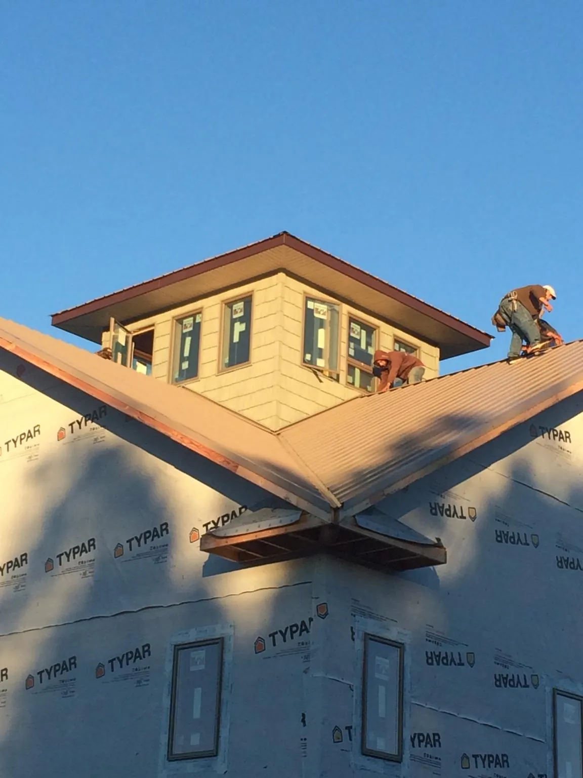 Roofers working around a rooftop cupola on a new metal roof at sunset — Roof Waterproofing in Arkport by Roofing Brothers